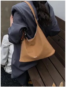 Detail of caramel brown large capacity hobo bag with unique wood bead pendant accessory
