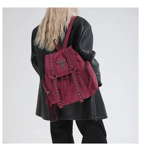 Detail of dark red vintage backpack featuring silver studs and gothic cross chain decoration