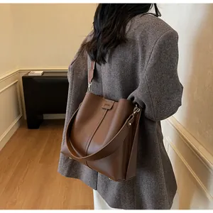 Gros plan d'un sac seau marron en similicuir avec coutures diagonales et large bandoulière