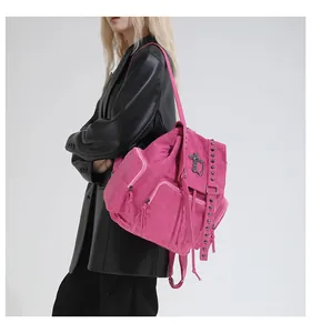 Close-up of pink suede backpack with metal rivets and decorative cross pendant detail