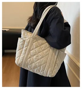 Detail of off-white quilted tote bag showing wide shoulder straps and side pocket utility
