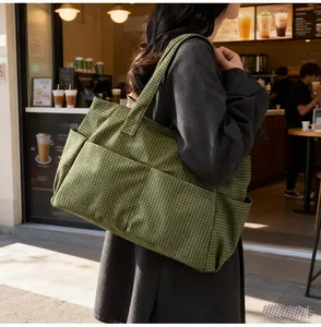 Détail d'un sac cabas en toile à carreaux verts avec des poches extérieures pratiques