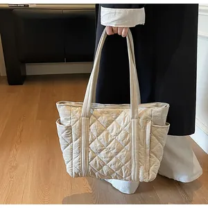 Detail of light beige quilted tote bag showing nylon texture and functional side pockets