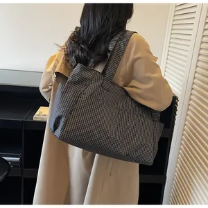Vue de dos d'une femme portant un sac cabas en nylon à carreaux dans un décor épuré