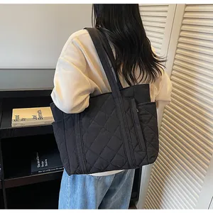 Detail view of black quilted tote bag showing large diamond stitching and side pocket