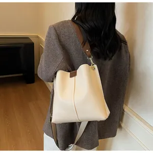 Détail du sac seau blanc cassé avec doubles bandoulières en cuir marron et métal doré