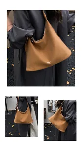 Detail of a large brown tote bag with beaded shoulder strap on an autumn leaf background