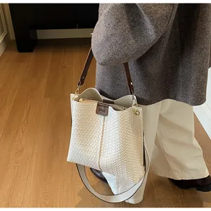 Détail du sac cabas blanc tressé avec poignées en cuir marron et bandoulière réglable