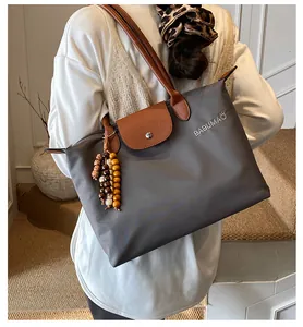 Détail du cabas en nylon gris foncé avec anses en cuir marron et perles décoratives