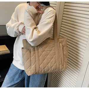 Detail of quilted stitching and side pocket on khaki down tote bag for daily commute
