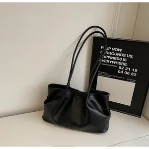 Détail de sac cabas en cuir noir plissé avec anses fines et texture mate élégante