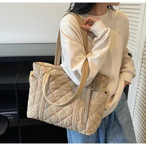Close-up of beige quilted tote bag showing embroidered patterns and side pocket detail