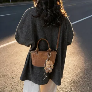 Vintage-Handtasche mit Leopardenmuster, Wildleder-Optik und Bärenanhänger im Abendlicht