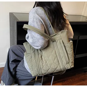Detailed view of the olive green quilted tote bag featuring side pockets and nylon texture