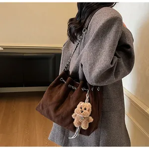 Detail of brown quilted bucket bag featuring a drawstring closure and plush bear charm