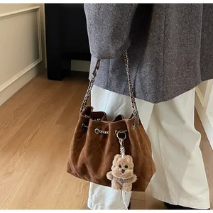 Detail of dark brown quilted suede bucket bag with silver chain and cute bear charm