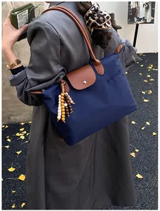 Détail d'un sac cabas en nylon bleu marine avec anses en cuir et breloque en perles