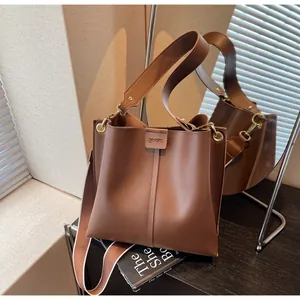 Détail du sac seau en cuir marron avec double bandoulière et fermoir à boucle en cuir gaufré