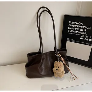 Détail du sac cabas en cuir marron foncé avec pendentif chien en peluche et texture douce