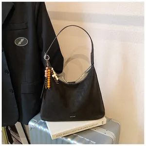 Close-up of large black hobo bag with retro beaded tassel detail and sleek logo