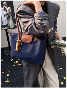 Détail du cabas en nylon bleu marine avec poignées en cuir et breloque en perles