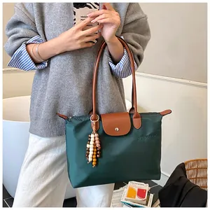 Détail du sac fourre-tout en nylon vert foncé avec anses en cuir et breloque perlée