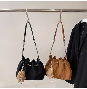 Detail of quilted bucket bags in black and brown with chain straps and bear charms