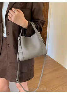 Detail of grey lychee leather bucket bag with top handle and crossbody strap