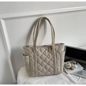 Detail of light khaki quilted tote bag with side pockets and elegant diamond pattern