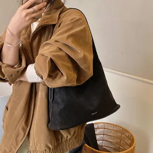 Minimalist black faux leather large tote bag shown as a casual shoulder bag on model