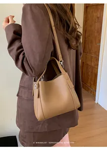 Close-up of brown lychee grain leather bucket bag with silver hardware on a model