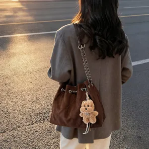 Quilted dark brown suede bucket bag with silver chain strap and plush bear charm