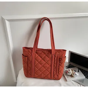 Detail of burnt orange quilted tote bag with diamond stitching and side pockets