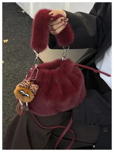 Close-up of fluffy burgundy plush bucket bag with monster charm and strap detail