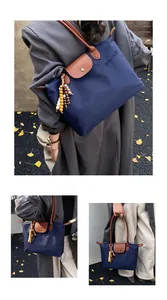 Détails de sac cabas en nylon bleu avec poignées en cuir marron et pompon en bois