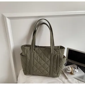 Detail of olive green quilted tote bag showing rhombus stitching and large side pockets