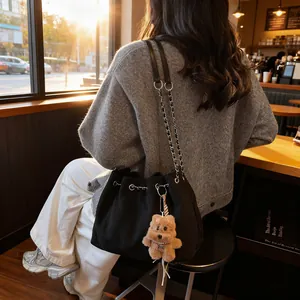 Chic black quilted bucket bag with chain strap and teddy bear charm for women