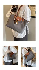Détail du sac cabas en nylon gris avec anses en cuir marron et pendentif décoratif en perles