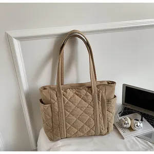 Detail of khaki quilted tote bag featuring large side pockets and soft diamond stitching