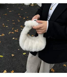 Close-up of white faux fur cloud bag with soft pleated texture held by a model