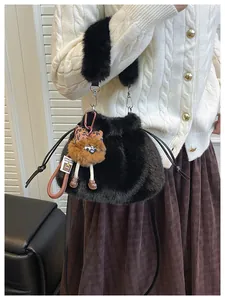 Detail of black faux fur bucket bag with plush monster charm and leather shoulder strap