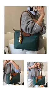 Détail du cabas en nylon vert foncé avec anses en cuir et breloque à pompon perlé