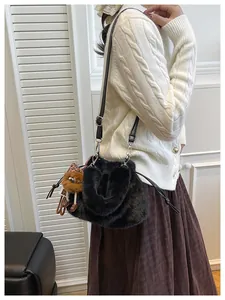Detail of black faux fur bucket bag with drawstring closure and cute plush bear charm