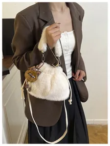 Detail of plush white bucket bag featuring a leopard bow bear charm and drawstring