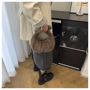 Detailed view of a soft brown faux fur crescent hobo bag held by a model in a cozy setting