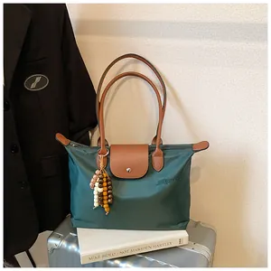 Détail du grand sac cabas en nylon vert foncé sur valise avec poignées en cuir et bijou