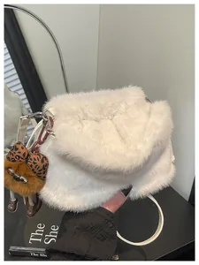 Detail of white faux fur tote bag with brown plush pendant and leather strap
