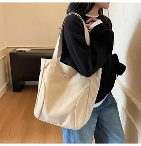 Detail shot of ivory canvas tote bag featuring premium cursive brand embroidery