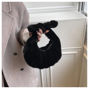 Detail of a black plush faux fur handbag with a knotted handle and soft pleated texture