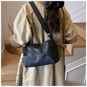 Détail du sac en nylon noir montrant la bandoulière réglable et la boucle argentée large
